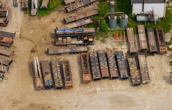 Aerial view of a logistics yard filled with numerous flatbed trailers and industrial equipment parked on a dirt lot in Vilnius, Vilnius County, Lithuania.