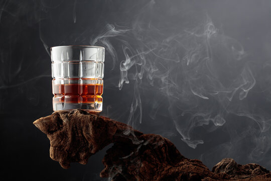 Smoked old-fashioned cocktail on weathered driftwood.