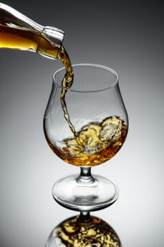 The amber-gold strong alcoholic beverage is poured into a glass.
