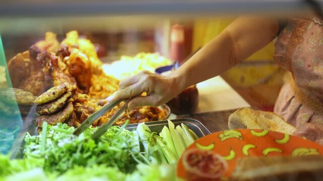 Street vendor hands making banh mi sandwich at food stall in Nha Trang, Vietnam. Close up view of traditional Vietnamese baguette filled with herbs, meat and ingredients at local fast food counter.