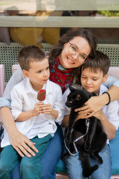A Caucasian woman with her two sons and a cat in a cafe. Pet-friendly outdoor cafe.