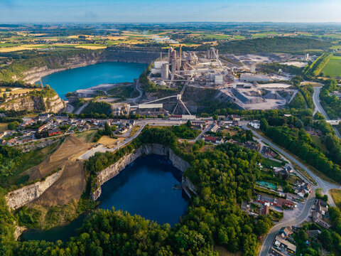 Aerial view of CCB Granulats Gaurain industrial facility featuring deep blue quarry lakes, processing infrastructure, and surrounding greenery in Tournai, Wallonia, Belgium.