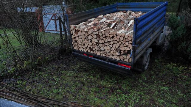 Truck delivering wood fuel for winter heating, dumping split firewood logs