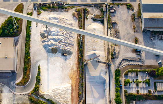 Aerial view of CCB Granulats Gaurain industrial site featuring large piles of gravel, conveyor belts, and facility buildings in Tournai, Wallonia, Belgium.