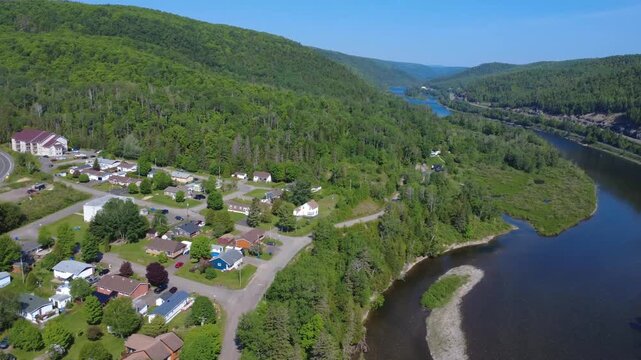 Scenic aerial view of the world-famous Matapedia salmon river flowing through the Appalachian Mountains and a peaceful residential community.