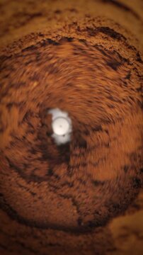 Ground Coffee Powder in Rotating Motion. Macro view of granular brown coffee swirling rapidly in a circular vortex.