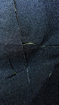 Dark Cracked Surface Texture. Close-up of rough black surface with deep irregular fractures and slow camera movement.