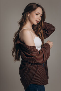 Girl with Long Brown Hair in Brown Sweater and White Tee on Light Background
