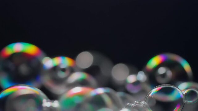 Macro close-up of iridescent rainbow soap bubbles on a dark background for abstract background and science concept