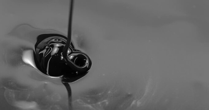 Black Viscous Liquid Pouring. Glossy fluid falls into a reflective pool, creating concentric ripples and swirling abstract forms.