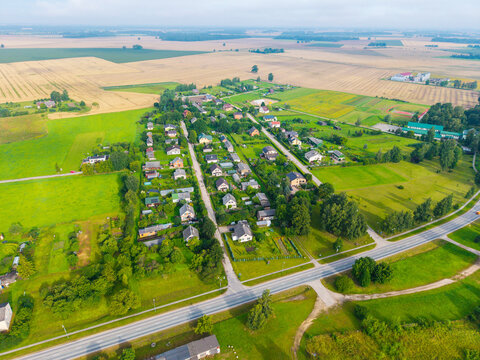 Aerial view of the village featuring scattered houses, lush green gardens, and surrounding agricultural fields in Jaunberze, Dobele Municipality, Latvia.