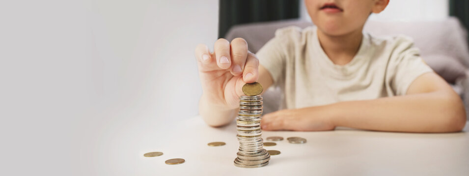 A little boy counts coins on a living room table. Financial scarcity training. Kids and money. Savings, personal finance. copy space banner