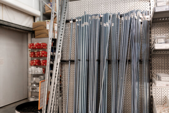Steel threaded rods and metal profiles standing vertically on display rack inside hardware home improvement store background construction materials warehouse retail market texture nobody
