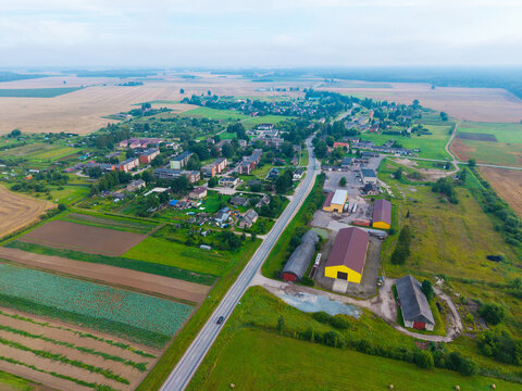 Aerial view of the rural village of Jaunberze with surrounding agricultural fields, a main road, and various residential and farm buildings, Jaunberze, Dobele Municipality, Latvia.