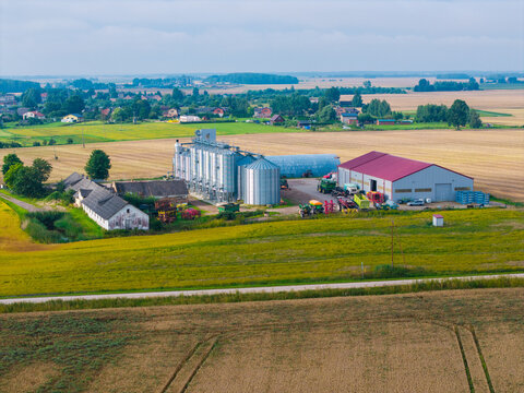 Aerial view of an agricultural facility featuring grain silos and farm buildings surrounded by vast fields in Jaunberze Parish, Dobele Municipality, Latvia.