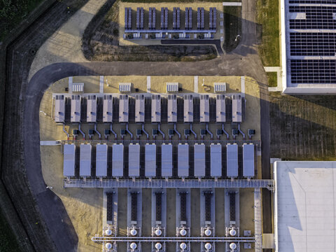 Aerial view of a modern data center facility featuring rows of industrial cooling units, complex infrastructure, and solar panels on the adjacent building roof in Illinois, United States.