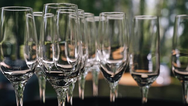A close-up of empty, clean glasses that are prepared for wine. People can be seen walking around with glasses out of focus