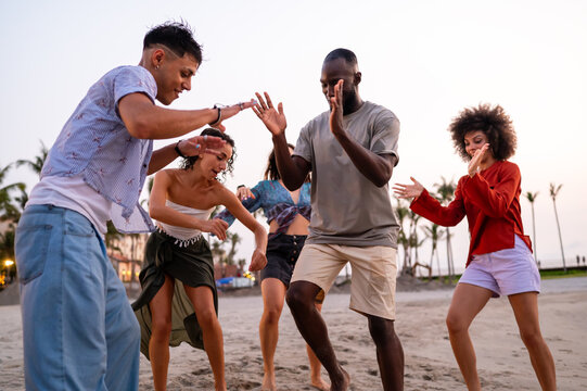 Joyful summer beach party with multiethnic friends celebrating vacation, enjoying music, freedom