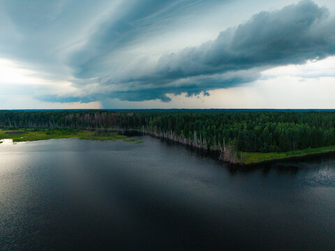 Aerial view of Kalnciema dolomite quarry with a dark storm cloud and heavy rain in the distance over the dense forest and lake in Valgunde Parish, Jelgava Municipality, Latvia.
