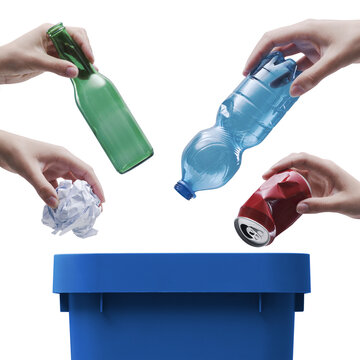 Hands Dropping Recyclable Materials into Blue Bin for Waste Sorting Concept