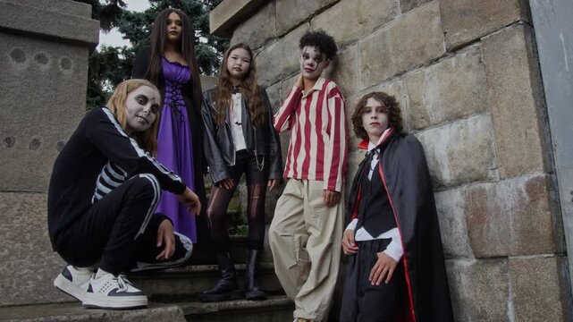 Portrait of diverse multiethnic teenagers wearing various Halloween costumes posing on stone steps. Clip is perfect for seasonal retail marketing and holiday event promotions
