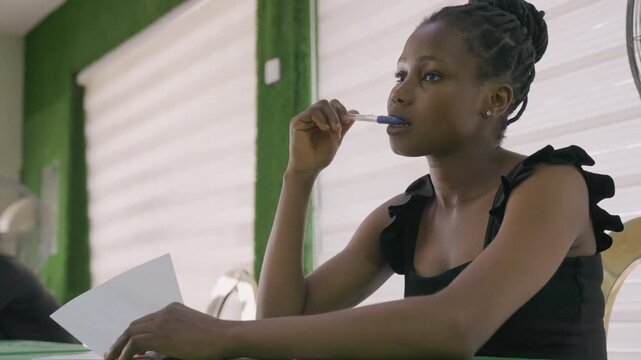 Young woman pondering letter with pen. Contemplative mood, lips touching pen, eyes scanning page, midday light through blinds, slow breath, hesitation before decision, intimate date planning