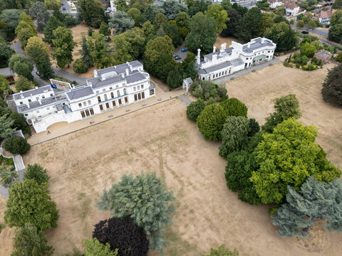 Aerial view of Gunnersbury Park Museum, featuring its historic white building set within expansive grounds with mature trees and dry grass in London, England, United Kingdom.