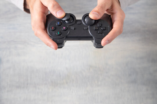 Male hands holding a black game controller.