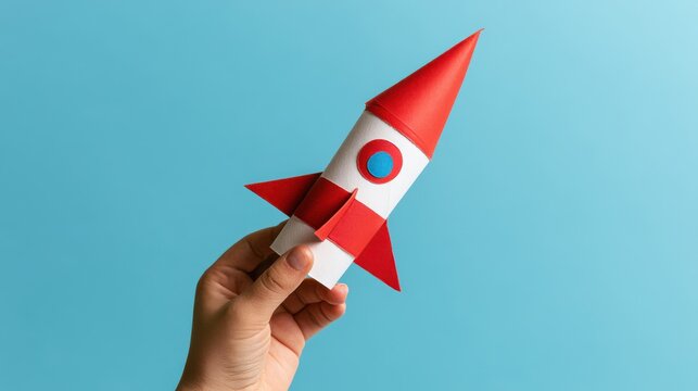 Hand holding paper rocket launching start-up concept