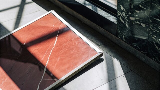 Abstract close-up of a red marble tabletop surface next to a glass window