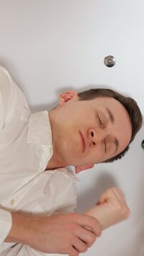 Unconscious businessman having an epileptic seizure in a bathtub, experiencing a stroke or heart attack from overwork, stress, or poisoning with saliva drooling from his mouth