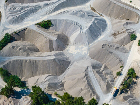 Aerial view of the Kiesgrube Breisach am Rhein-Niederrimsingen gravel pit, featuring large mounds of sand and gravel with winding access paths in Breisach, Baden-Wurttemberg, Germany.