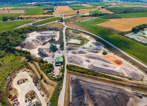 Aerial view of the Kiesgrube Breisach am Rhein-Niederrimsingen gravel pit with processing machinery, piles of sand and gravel, and agricultural fields in Breisach, Baden-Wurttemberg, Germany.