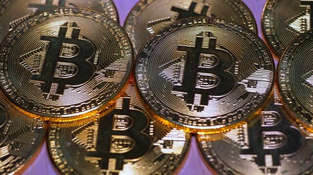 Shiny golden cryptocurrency tokens featuring distinct embossed symbols are arranged closely together in a tight cluster, highlighting the detailed texture and reflective polished metallic surfaces.