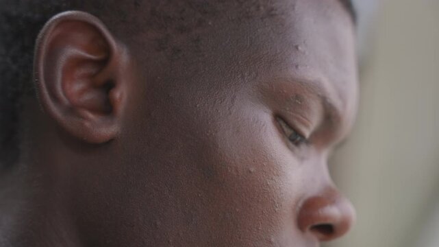Serene contemplative portrait. Gentle closeup of contemplative man with eyes shut and peaceful expression. Meditative black male figure captured in quiet stillness with gentle ambient lighting