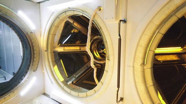 Space station closeup of three adjacent portholes with reflective gold trims and interior lighting tight framing highlights textures, seals and layered glass,