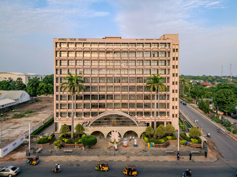 Aerial view of the Ahmed Talib House building, featuring its distinctive grid-patterned facade, palm trees, and surrounding urban street life in Nasarawa, Kaduna, Nigeria.