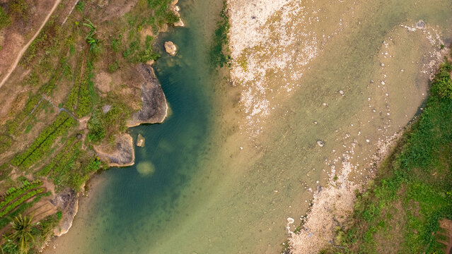 Aerial view of Sungai Oya with its rocky riverbed and lush green banks in Kecamatan Imogiri, Daerah Istimewa Yogya, Indonesia.