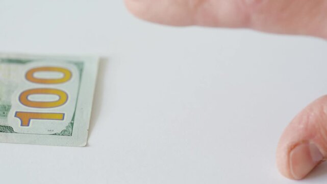 Hand reaching for hundred bill on white table, closeup of decisive motion office worker tempted to take payment, cashier making split decision, gambler testing impulse, contractor