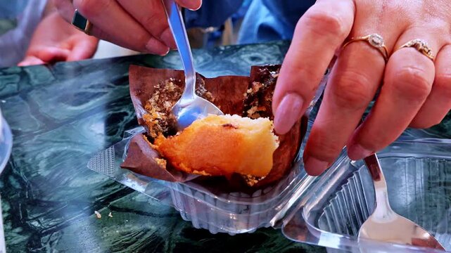 A silver spoon cuts into a warm chocolate dessert to reveal its rich center. Soft crumbs gather on the plate. Sweet treats enhance a visit at a caf� table.
