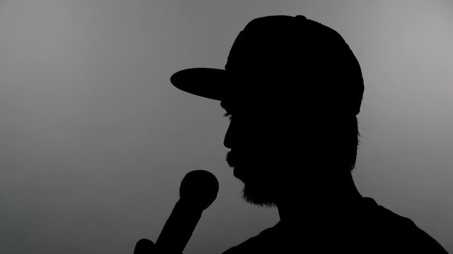 Close-up of an anonymous silhouette of a man giving an interview into a microphone against a white background