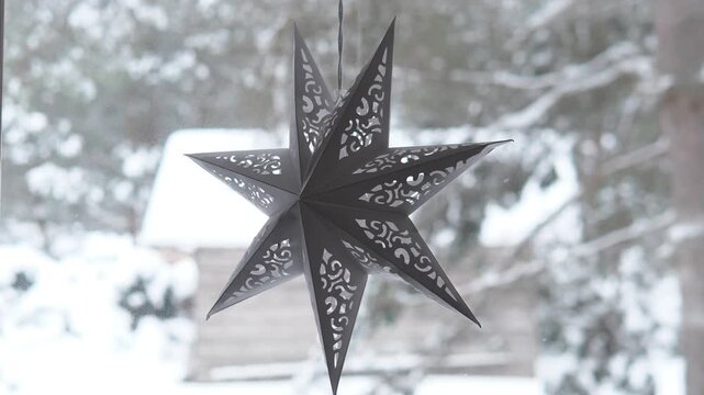 A serene outdoor snowy scene featuring hanging festive stars, holiday decorations and winter scenes. The setting is clean and natural, with white and gray tones and paper or cardb.