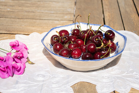 Fresh Ripe Cherries in Sunlight on a Rustic Cottage Garden Table