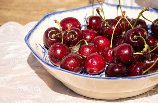Fresh Ripe Cherries in Sunlight on a Rustic Cottage Garden Table