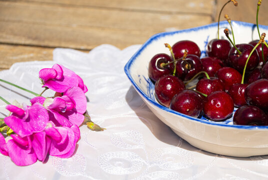 Fresh Ripe Cherries in Sunlight on a Rustic Cottage Garden Table