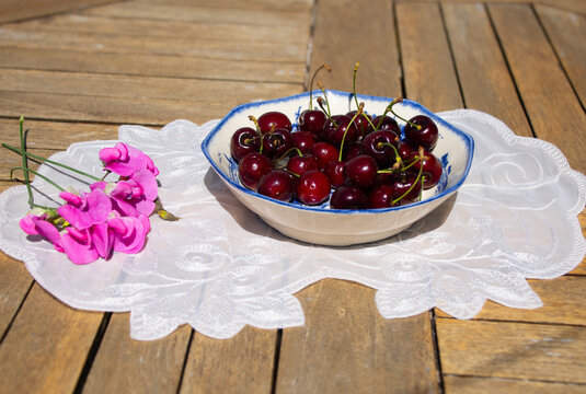 Fresh Ripe Cherries in Sunlight on a Rustic Cottage Garden Table