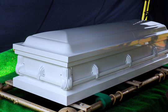 Coffin placed on stand covered with green fabric inside viewing area