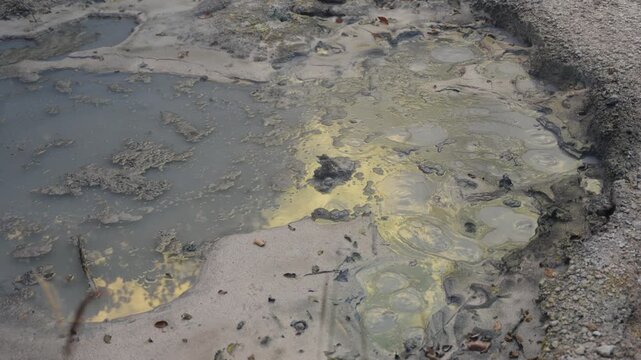 Geothermal activity with hot sulfuric gas bubbling through a muddy pond, creating a mesmerizing natural spectacle in a volcanic valley in Hokkaido, Japan, a famous tourist destination