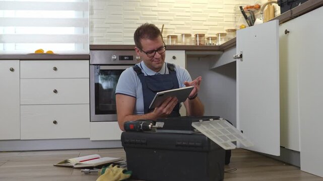 Frustrated handyman using a digital tablet for instructions in a kitchen