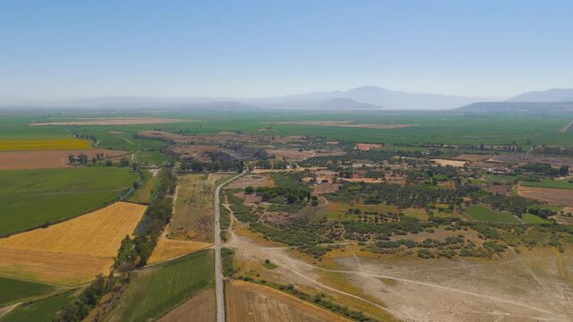 Balat, Turkey. Aerial drone panorama over the ancient city of Miletus, its sprawling archaeological ruins and silted harbor set against the green Meander floodplain under a clear summer sky. Aerial V